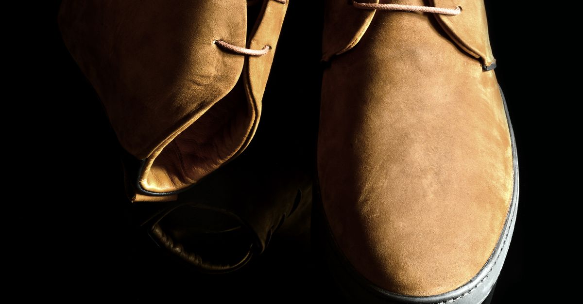 Close-up of a pair of tan suede boots against a dark background, highlighting the texture of the material.