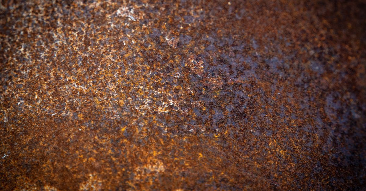Close-up of a rusted metal surface showing mottled orange and brown corrosion texture.