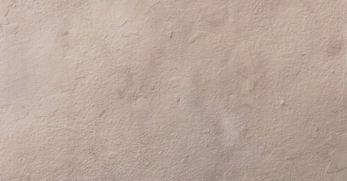 Close-up of a beige wall with a bumpy orange peel texture pattern across its surface.